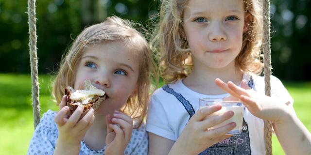 Deux petites filles qui grignotent une tartine de pain avec du beurre de Bresse AOP