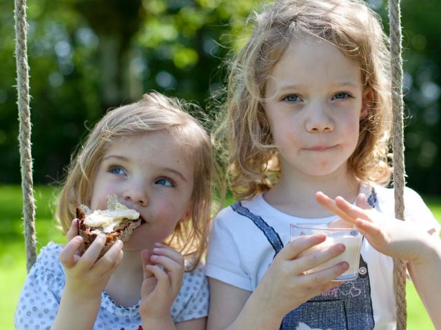 Deux petites filles qui grignotent une tartine de pain avec du beurre de Bresse AOP