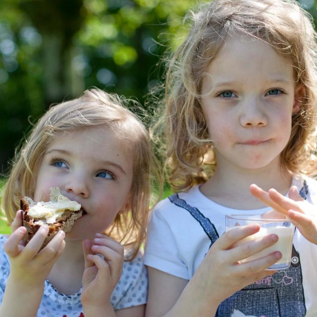 Deux petites filles qui grignotent une tartine de pain avec du beurre de Bresse AOP