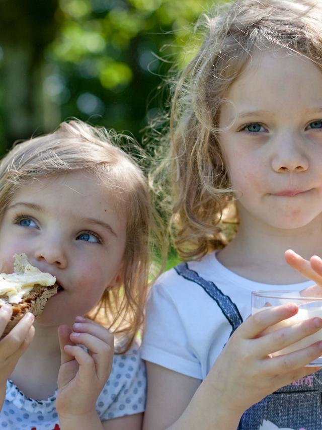 Deux petites filles qui grignotent une tartine de pain avec du beurre de Bresse AOP